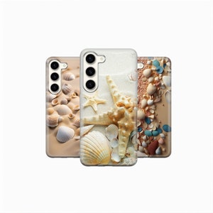 May include: Three phone cases with beach-themed designs. The cases feature images of seashells, starfish, and sand. The colors are primarily beige, white, and tan, evoking a coastal aesthetic. The cases are likely for smartphones.