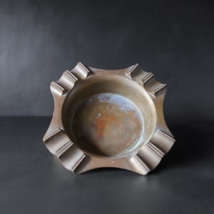 May include: A vintage brass ashtray with a starburst design and a slightly worn finish.
