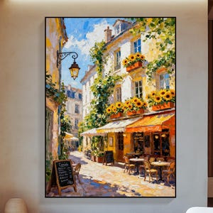 Könnte beinhalten: Ölgemälde einer europäischen Straßenszene mit einem Café. Das Kunstwerk zeigt einen sonnigen Tag mit blauem Himmel, gelben Gebäuden und orangefarbenen Markisen. Tische und Stühle sind vor dem Café aufgestellt, und Sonnenblumen befinden sich in Blumenkästen.