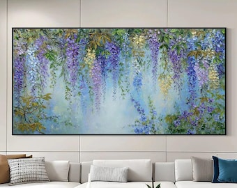 May include: A large rectangular painting featuring a floral design. The artwork showcases cascading wisteria blossoms in shades of purple, blue, and yellow against a soft, light blue background. The painting is framed in black and hangs above a white sofa.