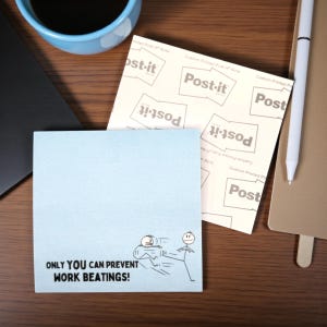 May include: A light blue Post-it note with the text "ONLY YOU CAN PREVENT WORK BEATINGS!" and a cartoon illustration of stick figures. A stack of Post-it notes and a pen are also visible on a wooden surface.