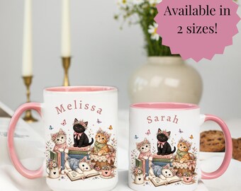 May include: Two white ceramic mugs with pink interiors and handles, featuring illustrations of kittens with flower crowns and books. The left mug is personalized with the name Melissa, and the right mug is personalized with the name Sarah.