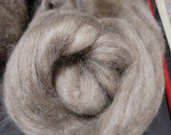 Könnte beinhalten: Nahaufnahme eines Bündels hellbraunen Wollrohlings. Die Wolle ist weich und flauschig und in einer lockeren, kreisförmigen Form angeordnet.