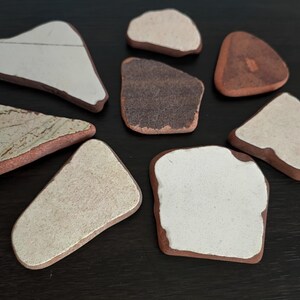 Peut inclure: Huit carreaux en céramique de formes et de tailles variées. Les carreaux sont blancs avec une bordure brune et certains ont un motif brun clair.