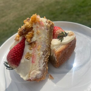 May include: Two slices of strawberry cheesecake with a graham cracker crust. The cheesecake is topped with whipped cream and fresh strawberries.