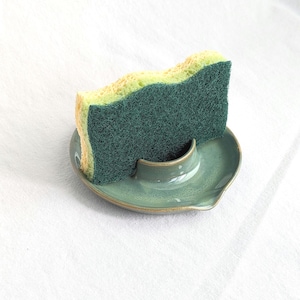 Peut inclure: Une éponge verte et jaune dans un porte-éponge en céramique bleu clair.