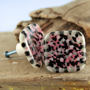 May include: Two square glass cabinet knobs with a pink, black, and white speckled pattern.