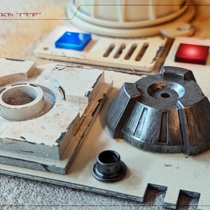 May include: A close-up of a model of a Star Wars Imperial AT-ST walker. The model is made of plastic and painted in a white and grey colour scheme. The model features a detailed cockpit, a rotating turret, and a pair of legs.