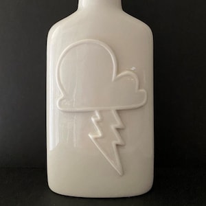 May include: White ceramic bottle with a raised design of a cloud and lightning bolt.