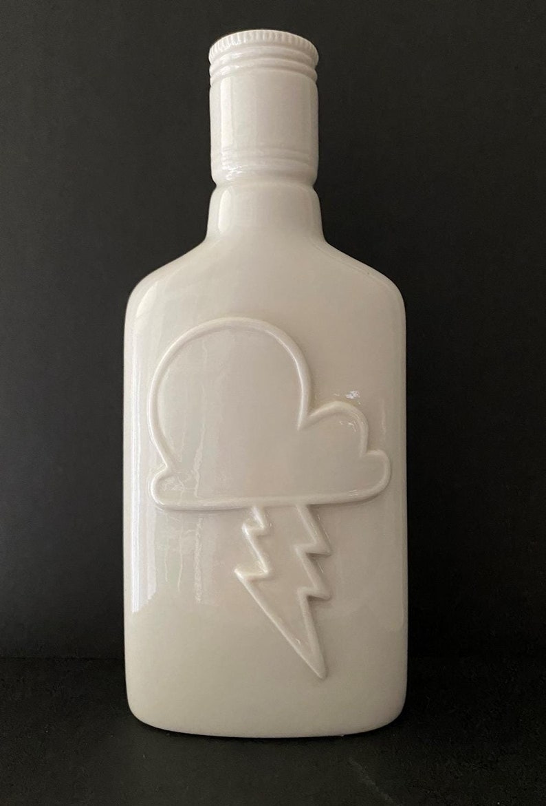 May include: White ceramic bottle with a raised design of a cloud and lightning bolt.