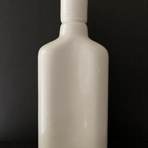 May include: A white ceramic bottle with a smooth, rounded shape and a simple, white lid.