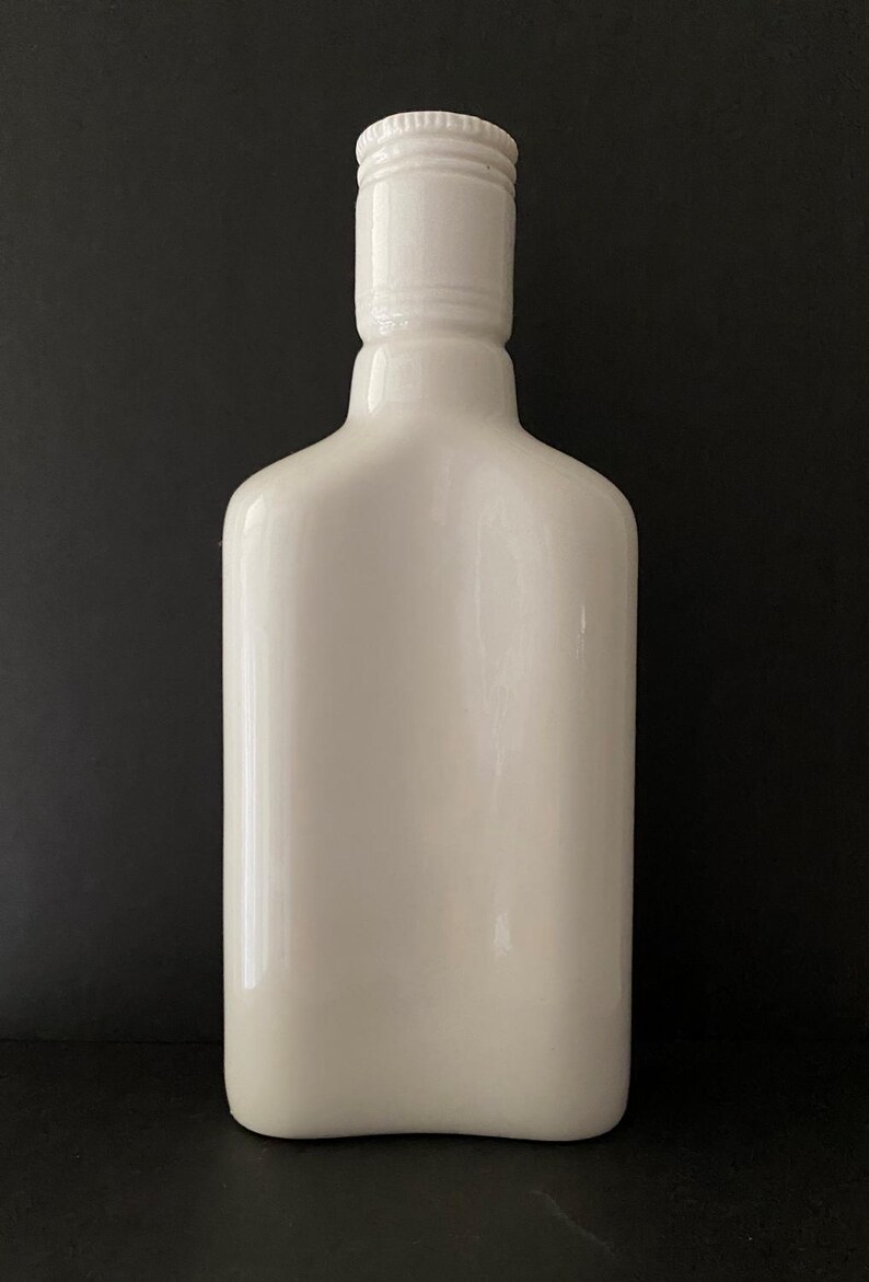 May include: A white ceramic bottle with a smooth, rounded shape and a simple, white lid.