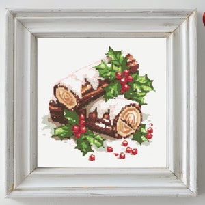 May include: A cross-stitch pattern of a yule log with white icing and holly berries. The log is surrounded by green holly leaves and red berries.