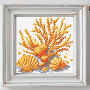May include: A cross-stitch pattern featuring a cluster of orange and yellow seashells surrounded by a coral branch. The seashells are arranged in a circular pattern, with the coral branch extending out from the center.