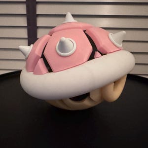 May include: A pink and white 3D printed shell with spikes, resembling a character from a video game.