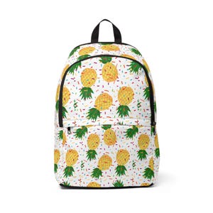 Puede incluir: Mochila blanca con un patrón repetido de piñas amarillas con hojas verdes y chispas de colores sobre un fondo blanco.