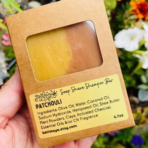 May include: A brown cardboard box with a window showing a yellow and orange soap bar. The box is labeled "Betha Kaya Soap Shave Shampoo Bar Patchouli" and lists the ingredients, "4.7oz", and the website "bethkaya.etsy.com".