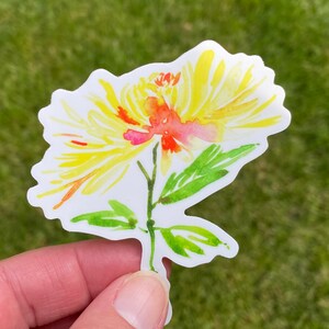 以下が含まれることがあります： 緑の葉が付いた黄色とオレンジの水彩画の花のステッカー。花は黄色い中心とオレンジとピンクの花びらを持っています。