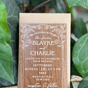 Pu&ograve; includere: Un invito di nozze con un design effetto legno. L'invito include i nomi "Blayke e Charlie" e i dettagli del matrimonio, tra cui data, ora e luogo. Sono presenti anche elementi floreali e bordi decorativi.