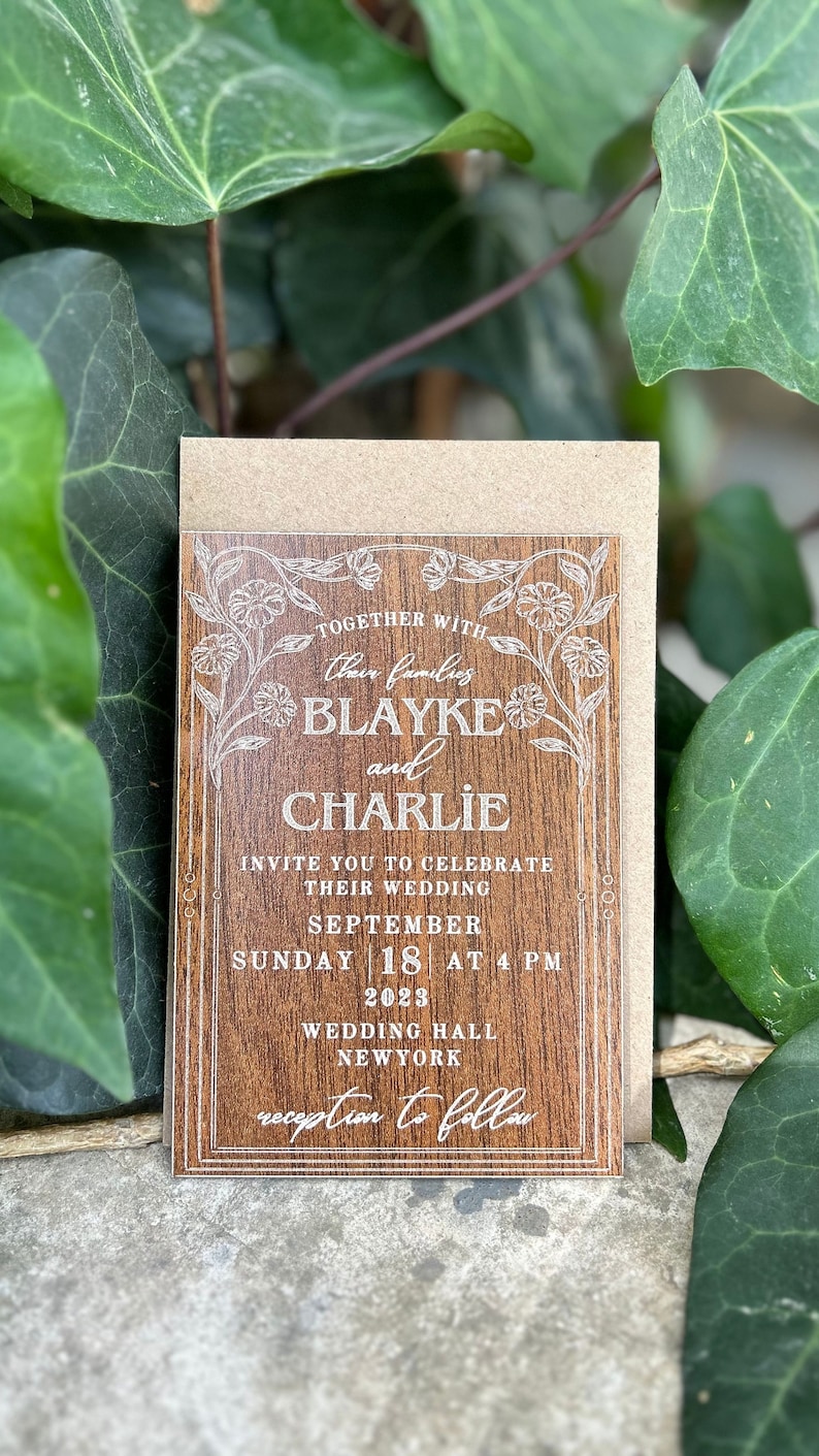 Pu&ograve; includere: Un invito di nozze con un design effetto legno. L'invito include i nomi "Blayke e Charlie" e i dettagli del matrimonio, tra cui data, ora e luogo. Sono presenti anche elementi floreali e bordi decorativi.