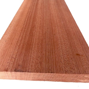 Può includere: Un pezzo rettangolare di legno marrone rossastro con un motivo a venature visibile. L'asse presenta una superficie liscia e piatta con bordi dritti, mettendo in risalto la consistenza naturale e le tonalità calde del materiale.