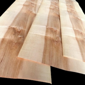 Può includere: Diversi fogli di impiallacciatura di legno di colore chiaro sono disposti in un motivo a strati. La venatura del legno presenta un mix di tonalità marroni chiare e medie, creando un aspetto naturale e strutturato. I fogli di impiallacciatura sono probabilmente per progetti di falegnameria.