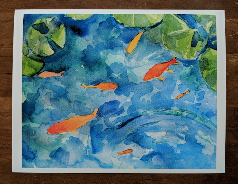 May include: Watercolor painting of a pond with lily pads and orange goldfish swimming. The water is a light blue color and the lily pads are green.