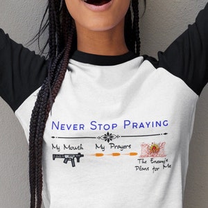 Puede incluir: Una camiseta de béisbol blanca y negra con el texto "Never Stop Praying" y un gráfico de una pistola, una flor y el texto "My Mouth, My Prayers, The Enemy's Plans for Me".