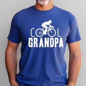May include: A royal blue t-shirt with a white silhouette of a person riding a bicycle and the text "COOL GRANDPA".