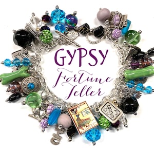 May include: A silver charm bracelet with various beads and charms in shades of blue, green, purple, and black. The bracelet includes a card that says "Tarot" and the text "Gypsy Fortune Teller".