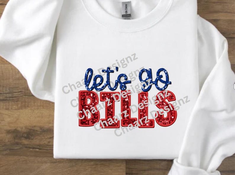May include: White long-sleeve sweatshirt with the text "let's go BILLS" in blue and red glitter lettering. The sweatshirt is made of a soft material and is perfect for game day or casual wear.