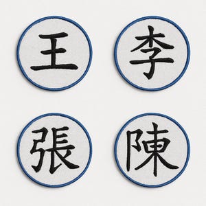 Può includere: Quattro toppe ricamate circolari. Ogni toppa ha uno sfondo bianco e un bordo blu. I caratteri cinesi neri sono centrati. Le toppe sono disposte in una formazione quadrata.