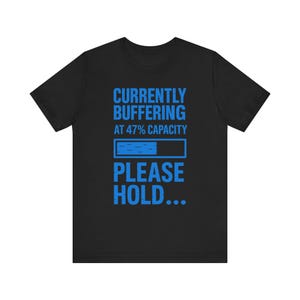 May include: Black t-shirt with the blue text "CURRENTLY BUFFERING AT 47% CAPACITY" and a loading bar graphic. Below the graphic, the text reads "PLEASE HOLD..."