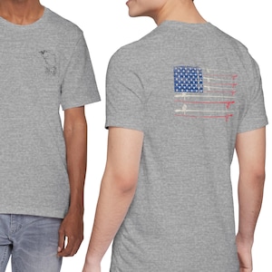 May include: A heather gray short-sleeve t-shirt featuring a small black graphic on the left chest and a large graphic on the back depicting an American flag composed of horizontal fishing rods with red, white, and blue color accents.