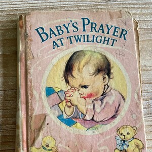 May include: A vintage children's book titled "Baby's Prayer at Twilight". The cover features a sweet illustration of a baby praying with a teddy bear and a duckling.