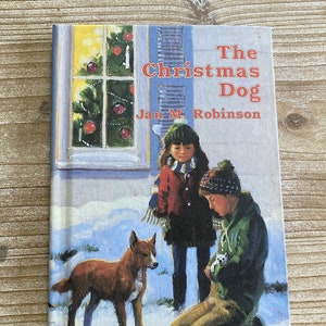 May include: A book cover featuring a winter scene with a girl and a boy with a dog. The book title is "The Christmas Dog" by Jan M. Robinson.