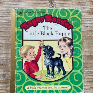 May include: A green and gold cover of a Little Golden Book titled "Eager Reader: The Little Black Puppy". The cover features a boy and a girl measuring a black puppy with a yellow tape measure.