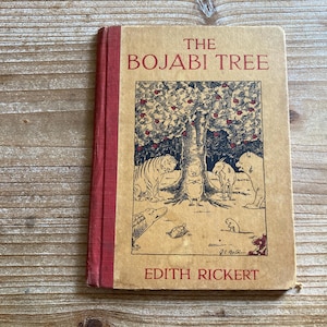 May include: A hardcover book titled The Bojabi Tree by Edith Rickert with a tan cover and a red spine. The front cover features a black ink illustration of a large tree surrounded by various animals including a tiger, a goat, and a bear.