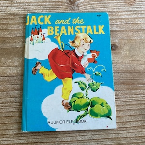 May include: A vintage children's book titled "Jack and the Beanstalk" with a blue cover and illustrations of a girl climbing a beanstalk with a rooster. The book is labeled "A Junior Elf Book".