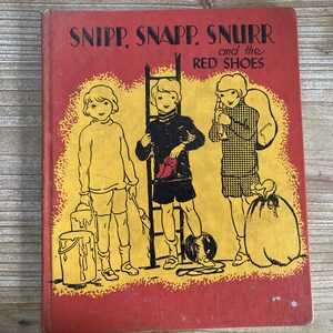May include: A vintage children's book cover with a red background and yellow accents. The title is "SNIPP, SNAPP, SNURR and the RED SHOES". The cover features three children, two boys and a girl, in black and white illustrations.