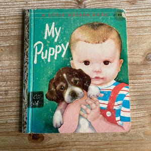 May include: Vintage children's book titled "My Puppy" with a teal cover. The cover features an illustration of a baby holding a brown and white puppy. The book is a "Little Golden Book" and has a price of 25¢.