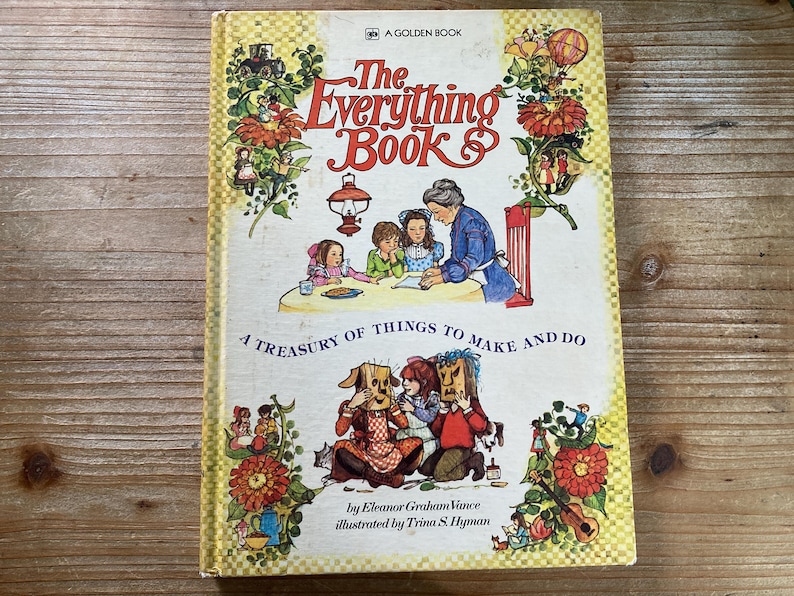 May include: A vintage Golden Book titled "The Everything Book." The cover features illustrations of children, adults, and whimsical characters. The book's title is in red script, with the subtitle "A Treasury of Things to Make and Do."