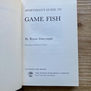 以下が含まれることがあります： バイロン・ダルリンプル著「スポーツマンズ・ガイド・トゥ・ゲーム・フィッシュ」というタイトルの白い本の表紙。本の表紙には、「ドグラス・アレンによる図版」と「アウトドア・ライフ・ブックス」の文字と、木のロゴが記載されています。