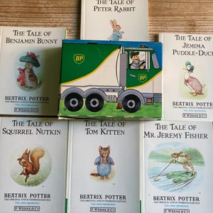 May include: A collection of Beatrix Potter books, including "The Tale of Benjamin Bunny," "The Tale of Peter Rabbit," and "The Tale of Jemima Puddle-Duck." A BP truck toy is also present. The books feature illustrations and the author's name.