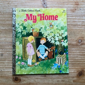 May include: A Little Golden Book titled "My Home" with a colorful illustration of two children and a dog standing in front of a wooden structure. The book cover features a green background with a tree and flowers.