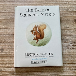 May include: A white book cover with the title "The Tale of Squirrel Nutkin" in black text. The cover features an illustration of a red squirrel holding a nut, surrounded by green foliage. The author, Beatrix Potter, is listed below the title, along with the text "The Original and Authorised Edition" and "New colour reproductions". The publisher, F. Warne & Co, is printed at the bottom of the cover.