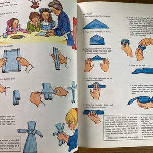 May include: Vintage illustrated instructions from a children's book, showing how to fold a handkerchief into a doll and a mouse. The illustrations are in color and feature people and hands demonstrating the folding steps.