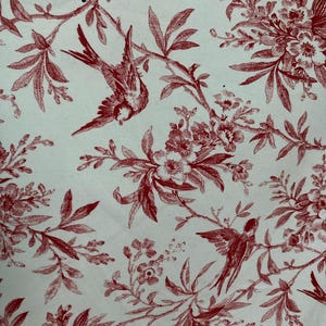 Könnte beinhalten: Rotes Blumenmuster auf weißem Hintergrund mit kleinen Vögeln, die durch die Zweige fliegen.