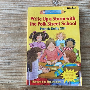 May include: A yellow children's book titled "Write Up a Storm with the Polk Street School" by Patricia Reilly Giff. The cover illustration shows children around a table. The book includes a special insert.