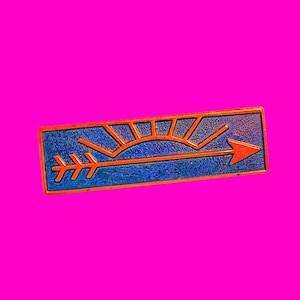 May include: A blue and orange enamel pin with a stylized sun and arrow design. The arrow points to the right and the sun has rays emanating from it.